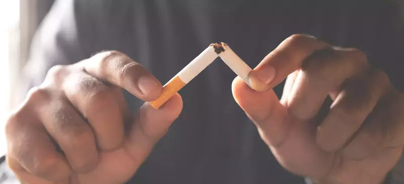 person breaking cigarette in half