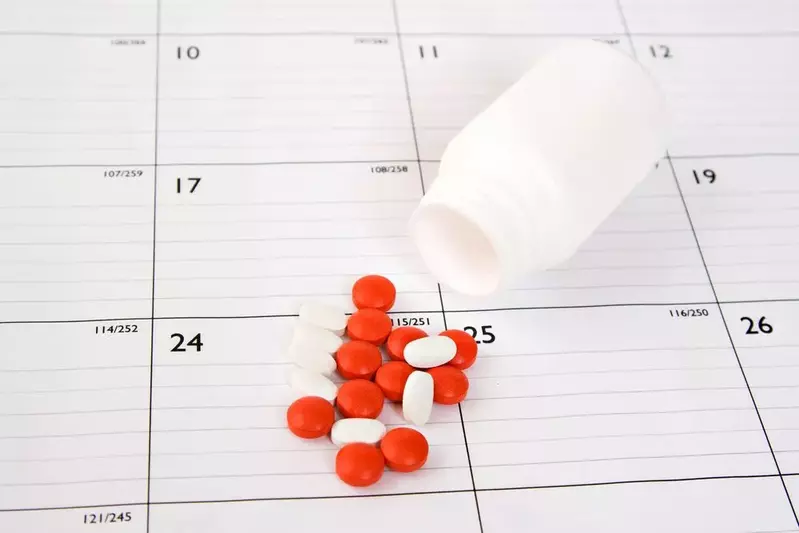 pills spilling out of bottle on top of a calendar